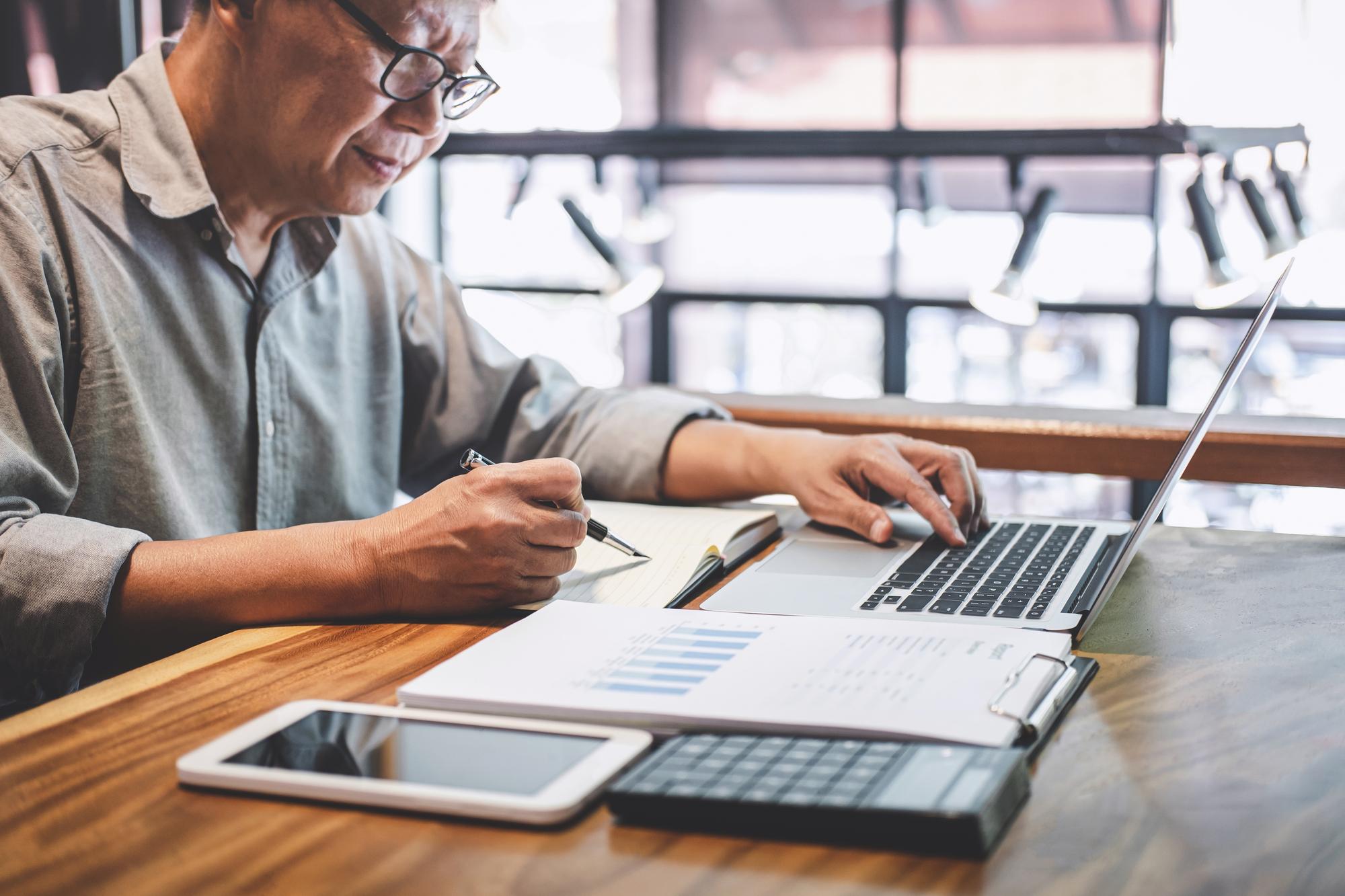 Person working with financial notes and laptop
